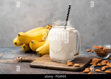 Banana protein smoothie in drinking glass on wooden serving board Stock Photo