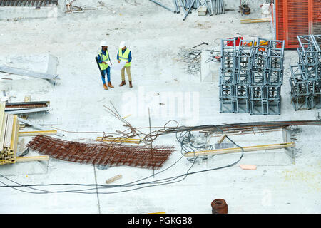 Wide angle shot of construction site with crew workers holding plans and  discussing project, copy space Stock Photo