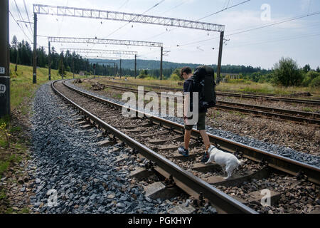 Teenager on railway walking with small white dog Stock Photo