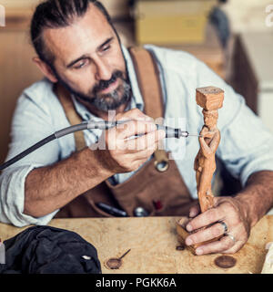 carpenter at work with electric drill on sculpture Stock Photo