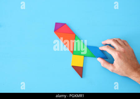 rocket made from tangram puzzle on blue pastel wooden background Stock Photo