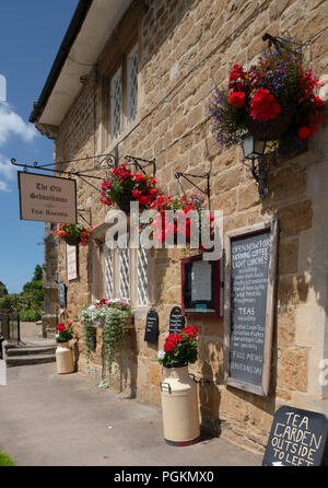 Colourful hanging baskets outside a tea room in Abbotsbury, Dorset, UK Stock Photo