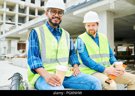 Portrait of two workers wearing hardhats  looking at camera during coffee break on construction site Stock Photo