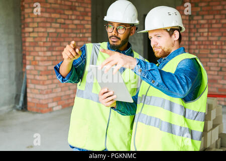Waist up portrait of two civil engineers wearing hardhats discussing construction on site, copy space Stock Photo