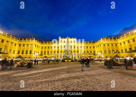 Schönbrunn Christkindlmarkt christmas market with illuminated palace and fairy lights decorated Christmas tree at dusk in Advent. Stock Photo