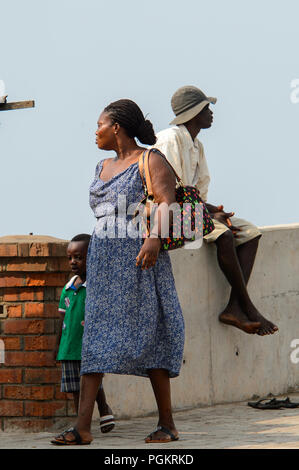 ELMINA, GHANA -JAN 18, 2017: Unidentified  Ghanaian woman walks with her child along the coast of Elmina. People of Ghana suffer of poverty due to the Stock Photo