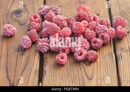 Raspberries covered with frost lie on wooden boards Stock Photo