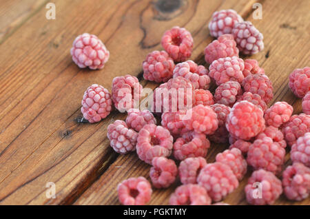 Raspberries covered with frost lie on a wooden background Stock Photo