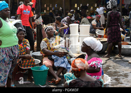 ELMINA, GHANA -JAN 18, 2017: Unidentified  Ghanaian women in colored clothes gather near Elmina port. People of Ghana suffer of poverty due to the bad Stock Photo