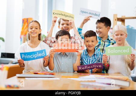 Smiling schoolschildren standing in the middle of a classroom Stock Photo
