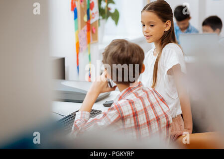 Pretty tired schoolgirl looking at the classmate Stock Photo