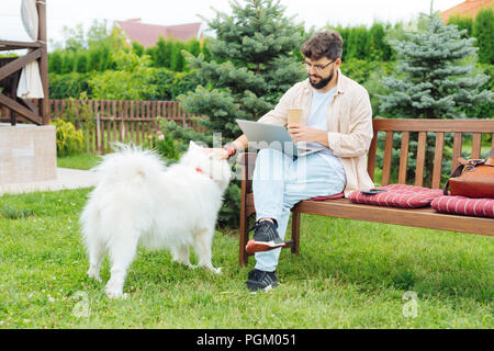 Bearded man sitting on the bench while working in home territory Stock Photo