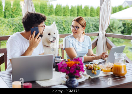 Busy dark-haired freelancer calling his business partner Stock Photo