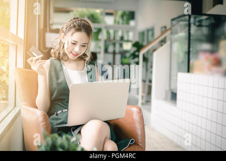 Beautiful Asian woman holding credit card and working on laptop or notebook computer. Stock Photo