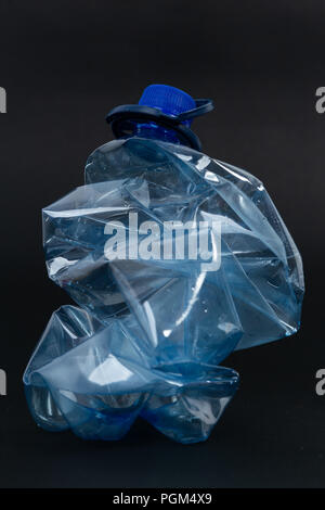 Crumpled recyclable plastic blue water beverage pet bottle as recycling single use pollution waste ecology concept isolated on black background Stock Photo