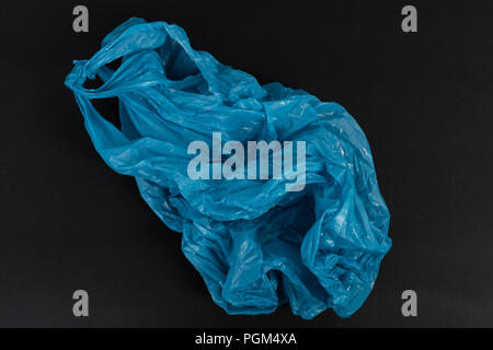 Old used crumpled blue shopping plastic or garbage bag as single use waste environment pollution concept isolated on black background Stock Photo