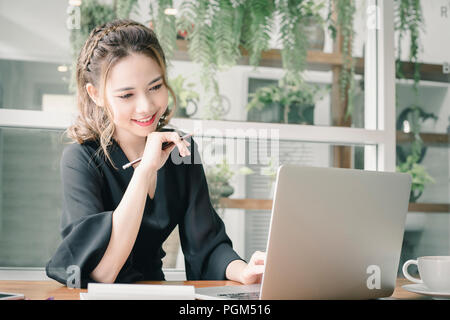 Confident happiness young woman working on laptop or notebook in her office. Beautiful Freelancer Woman working online at her home. Beauty Asian busin Stock Photo