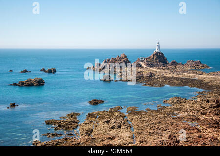 Landscape image of the Corbiere lighthouse in the south west corner of the island of Jersey with rocks in the foreground exposed by the low tide. Stock Photo