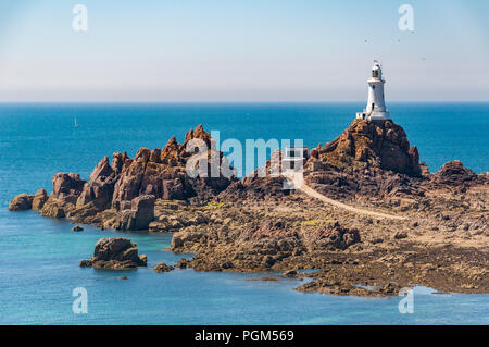 La Corbiere lighthouse on the island of Jersey. The causeway and the rocks surrounding the lighthouse are exposed at low tide. Stock Photo