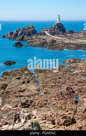 Portrait image of the Corbiere lighthouse in the south west corner of the island of Jersey with rocks in the foreground exposed by the low tide. Stock Photo
