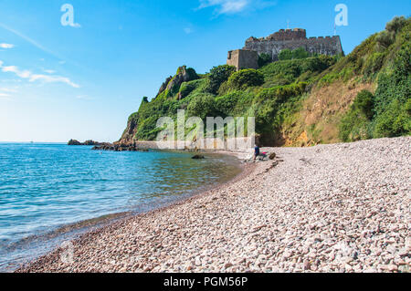 View of Mont Orgueil Castle on the island of Jeesey looking south from a secluded pebble beach towards the castle. Taken on a warm summers day Stock Photo