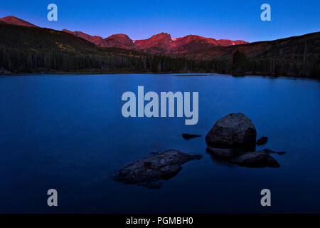 Sunlit peaks of the Rocky Mountains at sunrise at Sprague Lake, Rocky Mountain National Park, Colorado, USA Stock Photo