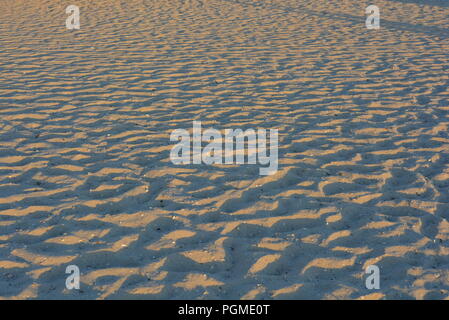 Yellow sand of the black sea at sunset with a blue shadow and golden color, very ordinary background. Stock Photo