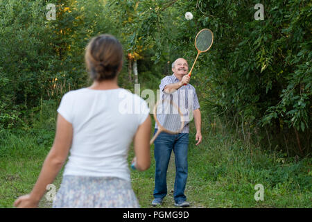 Mature man and girl playing badminton outdoors. Stock Photo