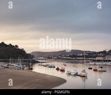 Boats moored in the Conway estauary at low tide as sun sets. Stock Photo