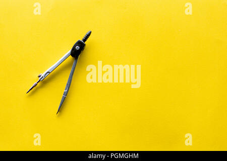 Drawing compass on a yellow background. Top view. Stock Photo