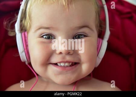 Beautiful baby in baby carriage playing with earphones unplugged Stock Photo