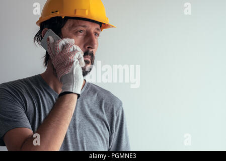 Construction engineer talking on mobile phone, serious adult male person using smartphone for communication with workers on building site Stock Photo