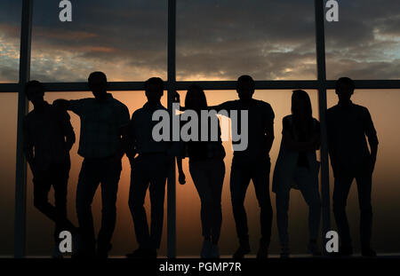 business team standing near the window, evening, dark Stock Photo
