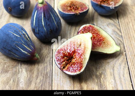 Fresh dark purple figs cut in halves on wooden surface Stock Photo