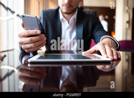 Young businessman working with modern devices, digital tablet computer and mobile phone. Stock Photo