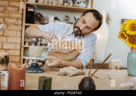 Creative potter smelling aroma sticks working with pottery wheel Stock Photo