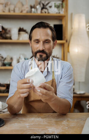 Bearded potter with facial wrinkles working in workroom Stock Photo