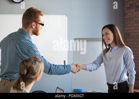 Male recruiter handshaking female job candidate after successful Stock Photo