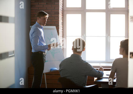 Serious male speaker presenting business strategy on flipchart  Stock Photo