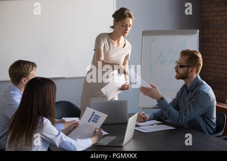 Female presenter giving handout materials to workers Stock Photo