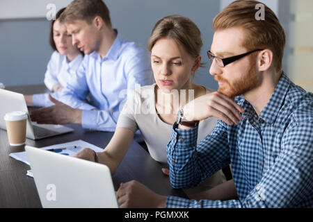 Concentrated workers busy at laptops discussing business project Stock Photo