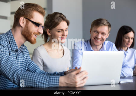 Smiling workers watching interesting video at laptop in office Stock Photo