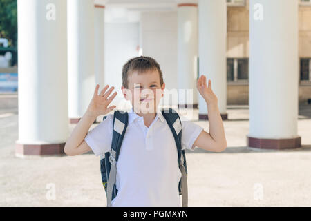 the boy is a first-grader in a white t-shirt with a gray backpack. different emotions. back to school Stock Photo