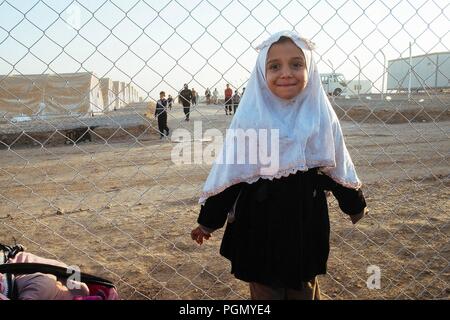 A refugee camp in Iraq, where live people escaped from ISIS. A young girl in front of the fences. Stock Photo