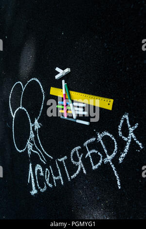 white chalk on black asphalt inscription in Russian September 1. yellow line, colorful markers, painted balls Stock Photo