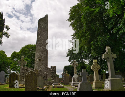 Various grave crosses and gravestones in a cemetery with round tower in the background Stock Photo