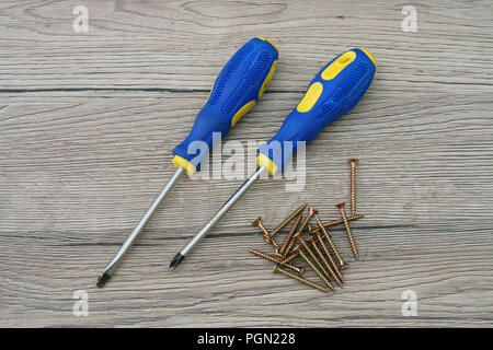 Screwdrivers and Screws Isolated on Wooden Desk. DIY Do it yourself tools on the table. Stock Photo