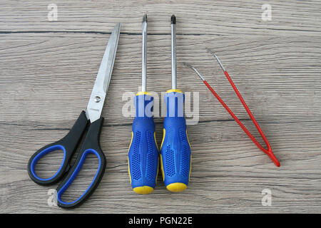 Scissor, Screwdriver and Tweezers Isolated on Gray Wooden Desk Stock Photo