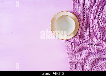 Empty white coffee cup  on violet background, close up photo knitted sweater with mug, winter morning concept. Top view. Flat lay Stock Photo