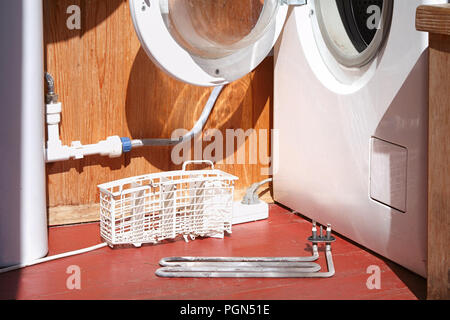 damaged washing machine heating element on the foor Stock Photo